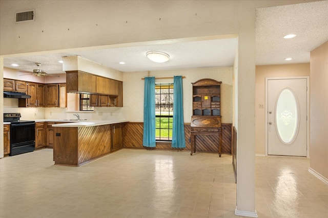 kitchen featuring visible vents, light countertops, black range with electric cooktop, under cabinet range hood, and brown cabinets