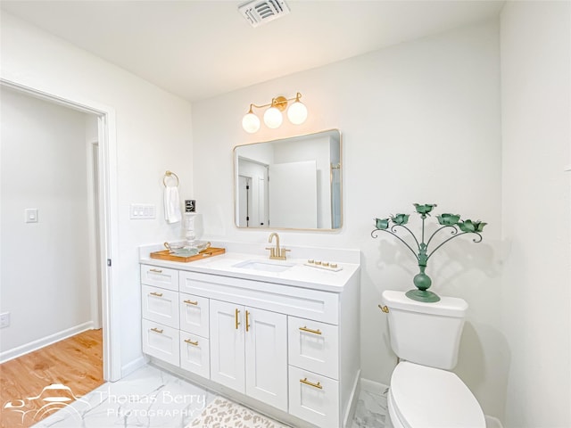 bathroom with vanity, toilet, baseboards, and visible vents