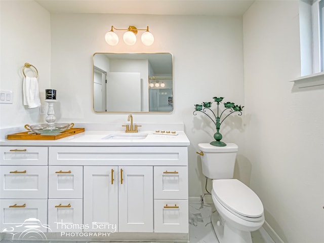 bathroom featuring vanity, toilet, baseboards, and marble finish floor