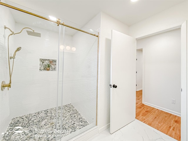 full bath with wood finished floors, baseboards, and a stall shower