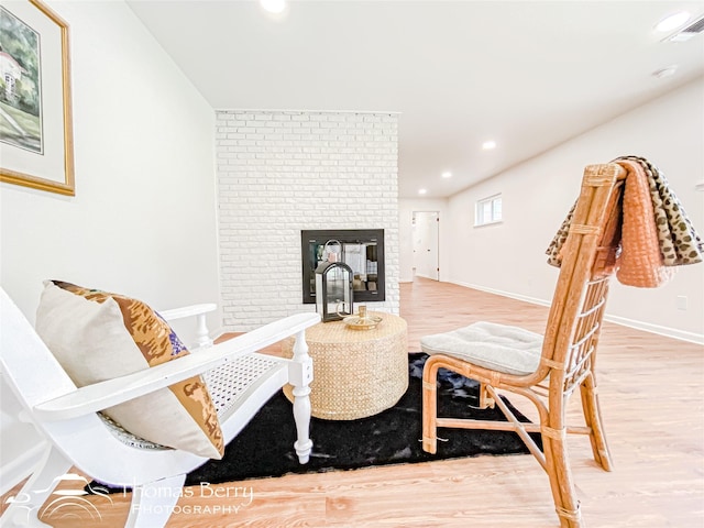 interior space featuring visible vents, a glass covered fireplace, wood finished floors, recessed lighting, and baseboards