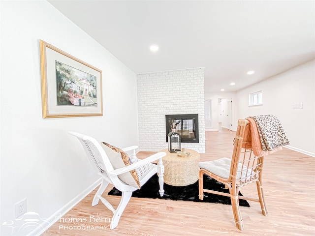 living area featuring recessed lighting, a fireplace, baseboards, and wood finished floors