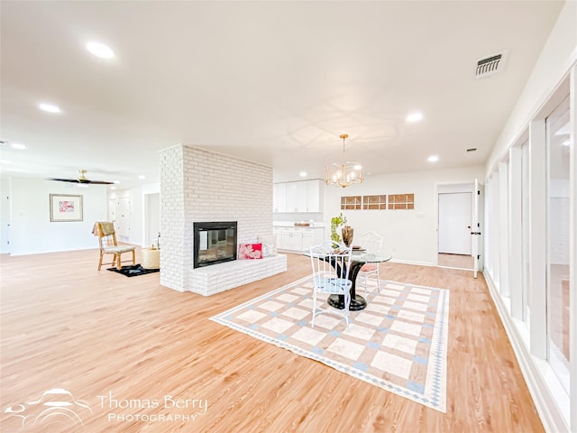 living area featuring a brick fireplace, recessed lighting, visible vents, and light wood finished floors