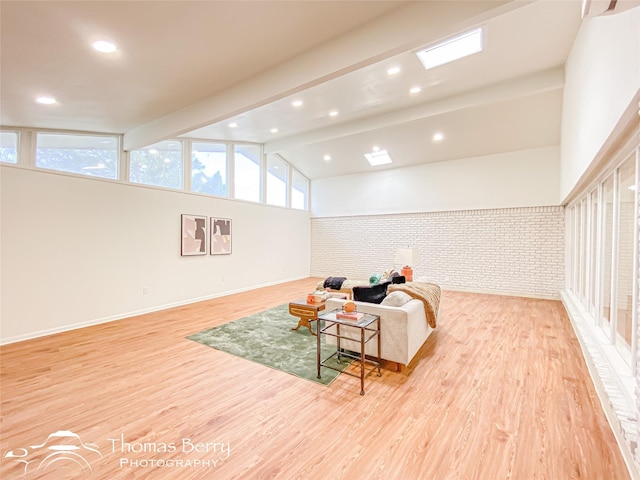 living area with baseboards, brick wall, lofted ceiling with beams, recessed lighting, and light wood-style floors