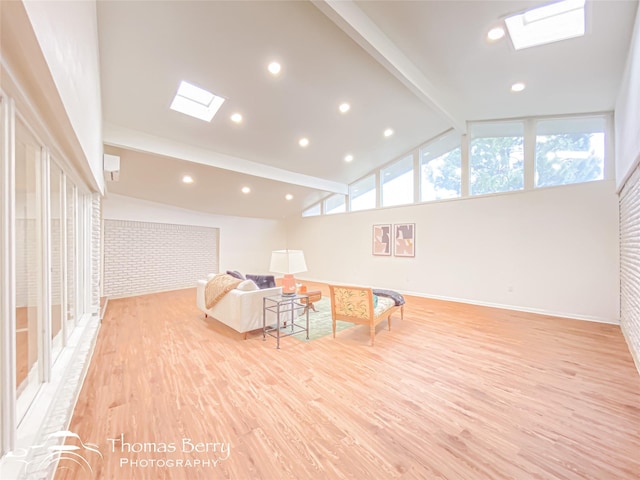 living area featuring vaulted ceiling with skylight, recessed lighting, light wood-style flooring, and baseboards