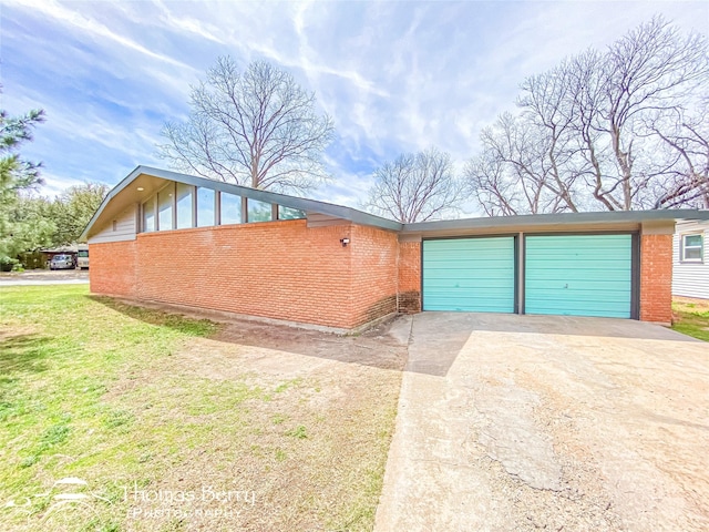 exterior space featuring a front yard, brick siding, concrete driveway, and an attached garage