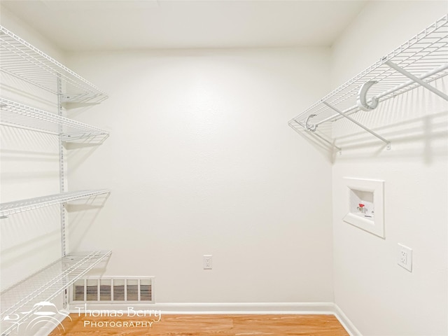 laundry room with visible vents, light wood-style flooring, baseboards, hookup for a washing machine, and laundry area