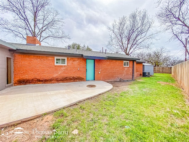 back of house featuring brick siding, central AC, a yard, a fenced backyard, and a patio