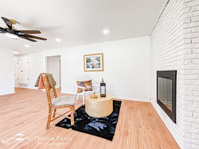 sitting room with baseboards, visible vents, light wood-type flooring, and ceiling fan