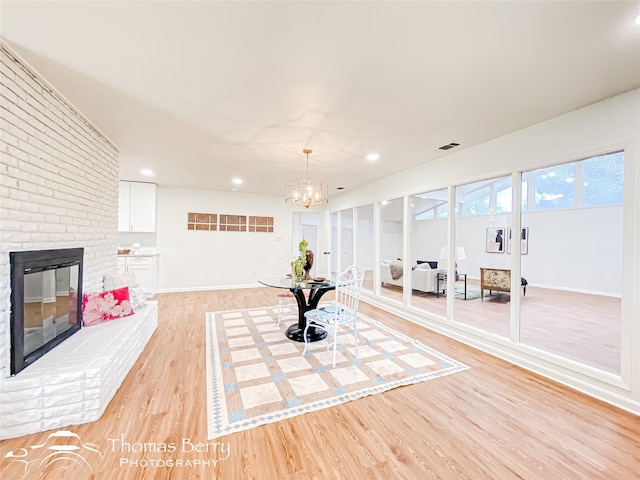 workout room with visible vents, light wood-type flooring, recessed lighting, a fireplace, and a notable chandelier