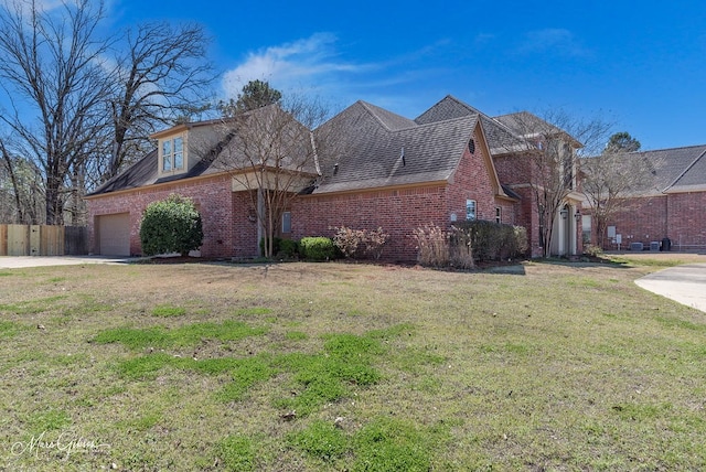 view of front of property with a front lawn, driveway, fence, an attached garage, and brick siding