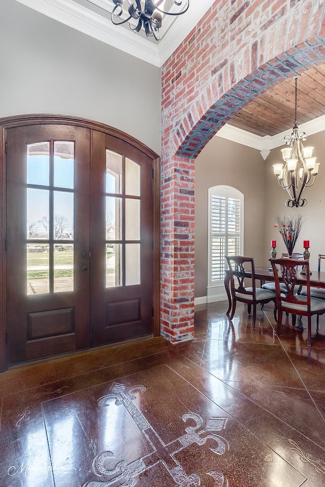 foyer entrance featuring baseboards, an inviting chandelier, arched walkways, french doors, and crown molding