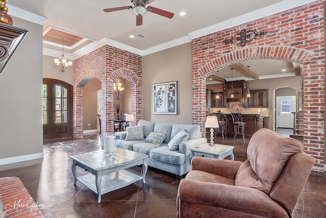 living room featuring ceiling fan with notable chandelier, crown molding, baseboards, and arched walkways