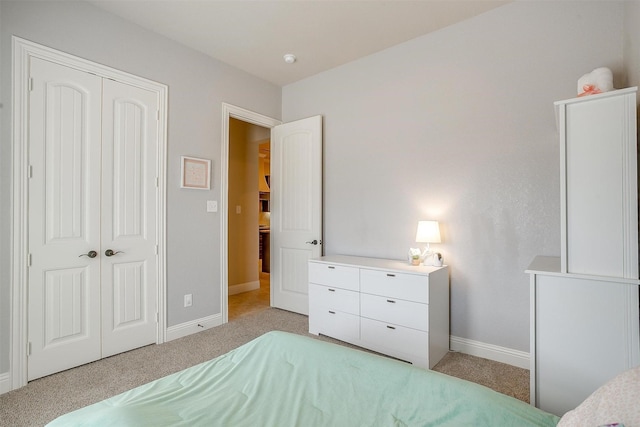 bedroom with baseboards, a closet, and light carpet