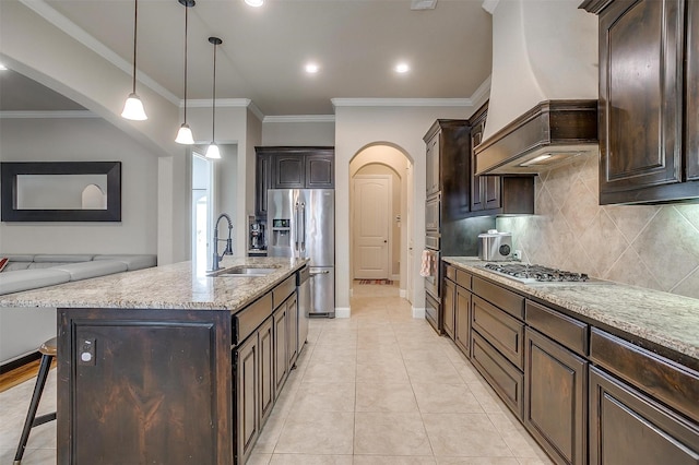 kitchen with a sink, appliances with stainless steel finishes, a breakfast bar area, custom exhaust hood, and dark brown cabinets