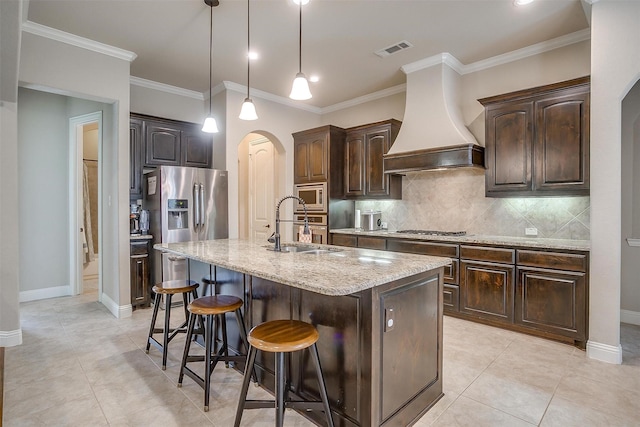 kitchen with visible vents, premium range hood, light stone counters, appliances with stainless steel finishes, and arched walkways