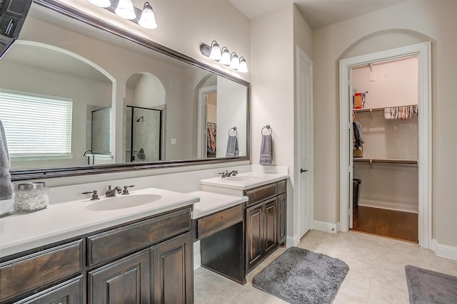 bathroom with vanity, a shower stall, a spacious closet, and tile patterned flooring