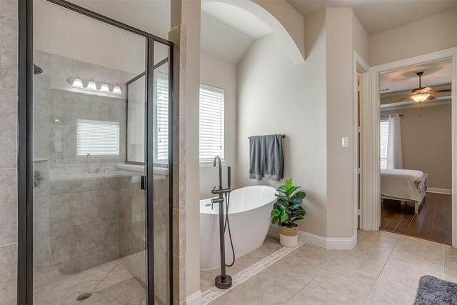 bathroom featuring a ceiling fan, baseboards, a soaking tub, a shower stall, and ensuite bathroom