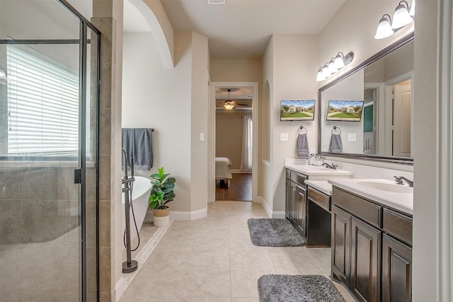 full bath featuring double vanity, a freestanding tub, a stall shower, ceiling fan, and a sink