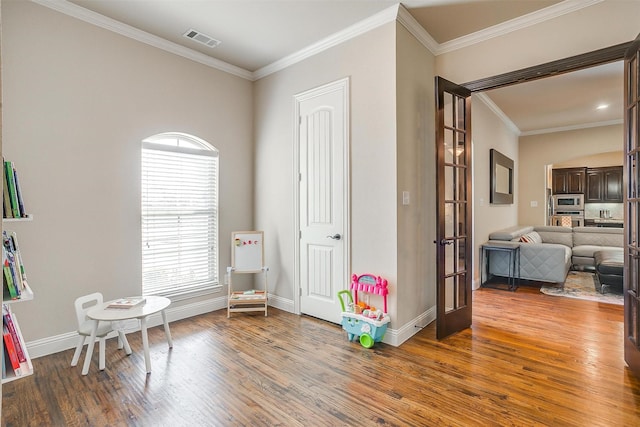 recreation room featuring visible vents, ornamental molding, wood finished floors, french doors, and baseboards