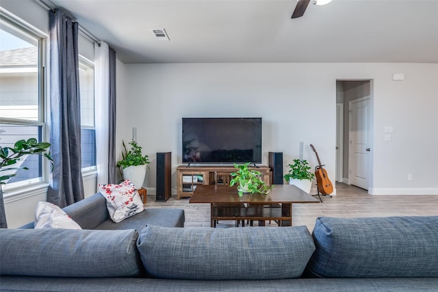 living room featuring visible vents, light wood-style flooring, baseboards, and a ceiling fan