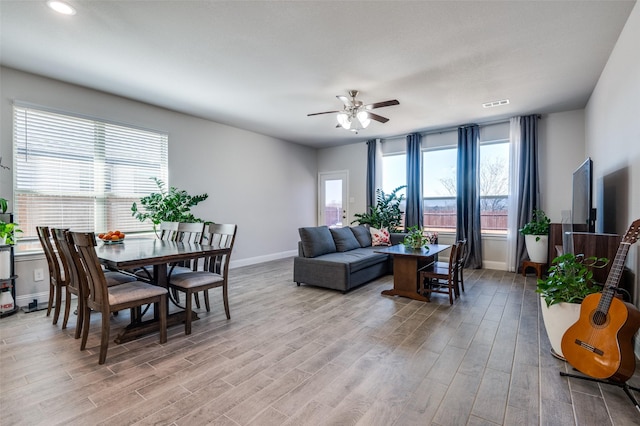 living room featuring ceiling fan, visible vents, baseboards, and light wood-type flooring