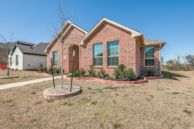 ranch-style house with a front yard and brick siding