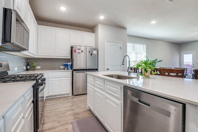 kitchen featuring wood finish floors, recessed lighting, a sink, appliances with stainless steel finishes, and tasteful backsplash