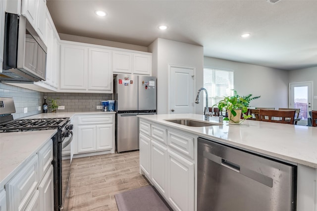 kitchen with a sink, appliances with stainless steel finishes, a wealth of natural light, and tasteful backsplash