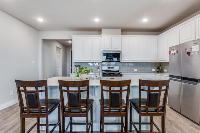 kitchen featuring tasteful backsplash, light wood-style flooring, appliances with stainless steel finishes, and light countertops