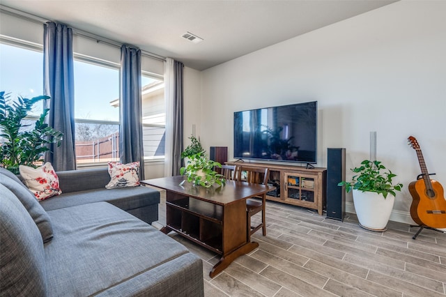 living room featuring baseboards, visible vents, and wood finish floors