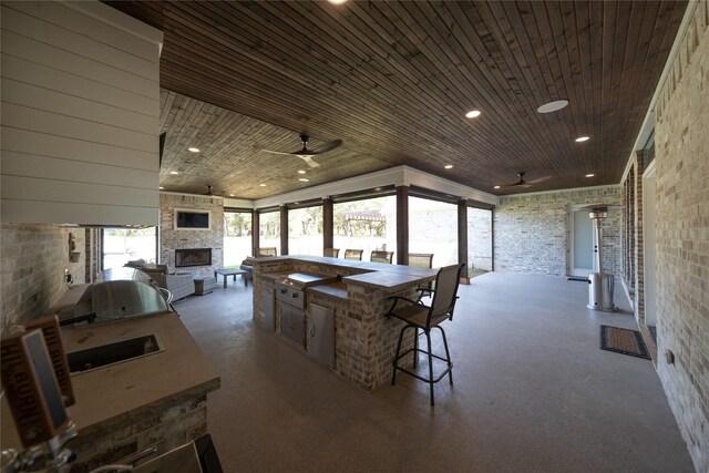 dining area featuring brick wall, wood ceiling, a fireplace, and a ceiling fan