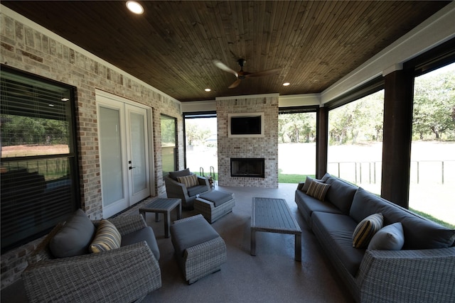 interior space with an outdoor living space with a fireplace, ceiling fan, and fence