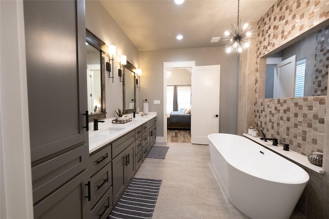 ensuite bathroom featuring a notable chandelier, a sink, ensuite bath, double vanity, and a freestanding bath