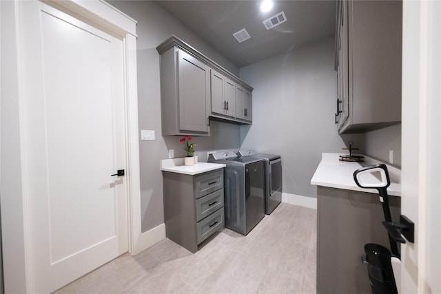 laundry room featuring washing machine and clothes dryer, visible vents, cabinet space, and baseboards
