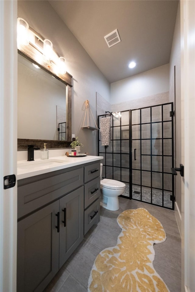 full bathroom featuring tiled shower, toilet, vanity, and visible vents