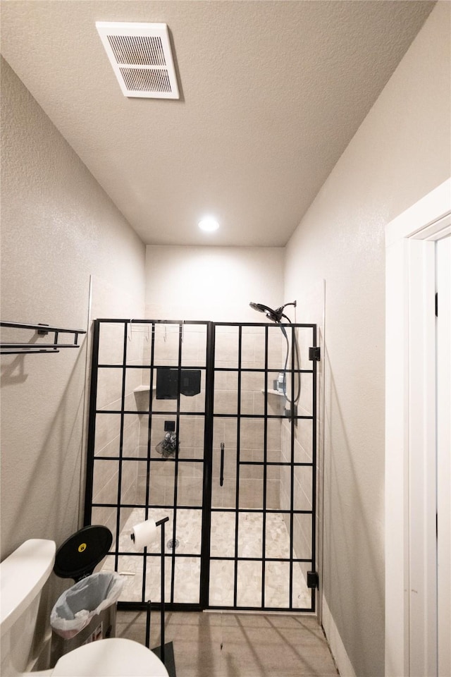bathroom featuring visible vents, a textured ceiling, and a walk in shower