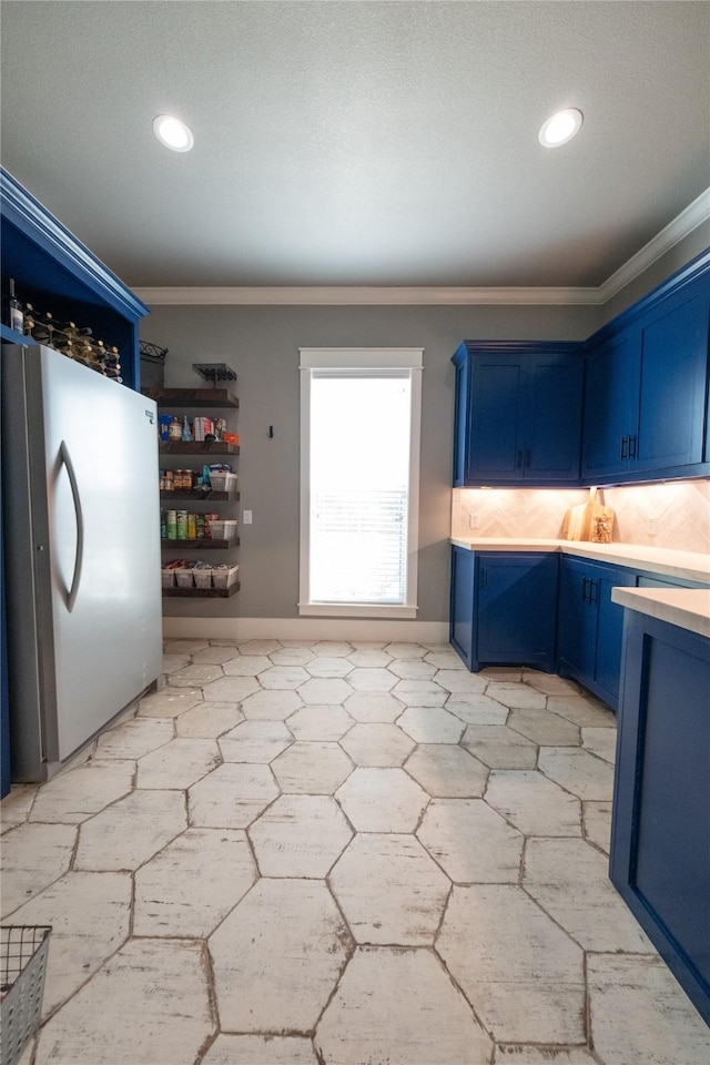 kitchen with recessed lighting, freestanding refrigerator, light countertops, crown molding, and blue cabinets