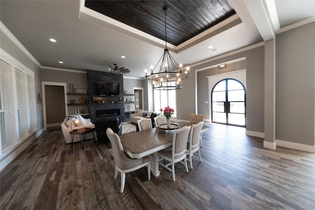 dining space with baseboards, a raised ceiling, dark wood-style floors, and a fireplace