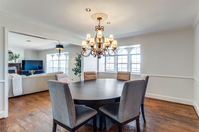 dining room featuring dark wood-type flooring, crown molding, a healthy amount of sunlight, and a chandelier