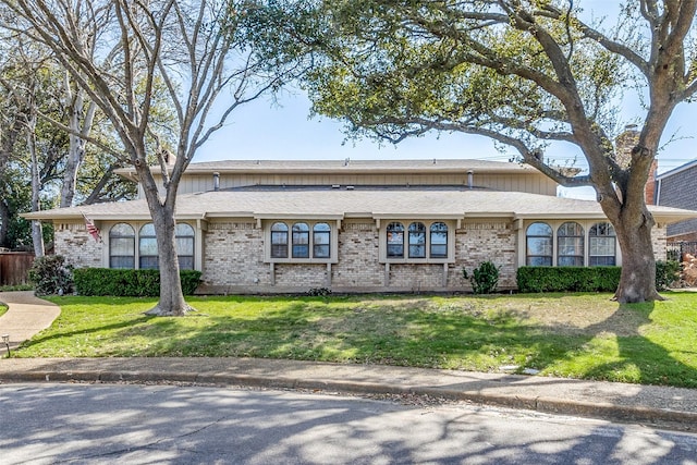 single story home with brick siding, roof with shingles, and a front yard