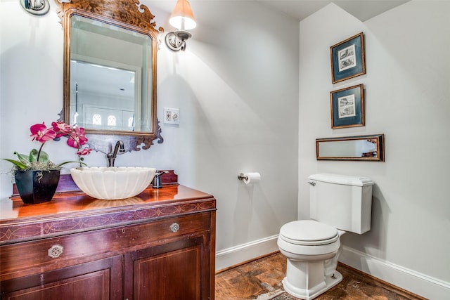 half bathroom featuring toilet, vanity, and baseboards