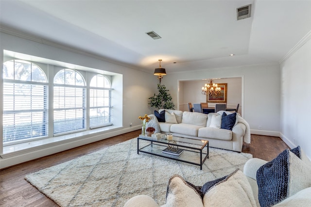 living room featuring visible vents, a notable chandelier, wood finished floors, and crown molding