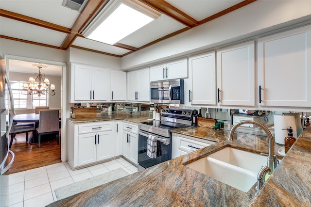 kitchen featuring a chandelier, light tile patterned floors, white cabinets, stainless steel appliances, and a sink