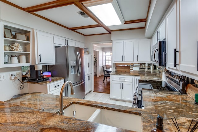 kitchen featuring dark stone countertops, stainless steel appliances, light tile patterned floors, and white cabinetry