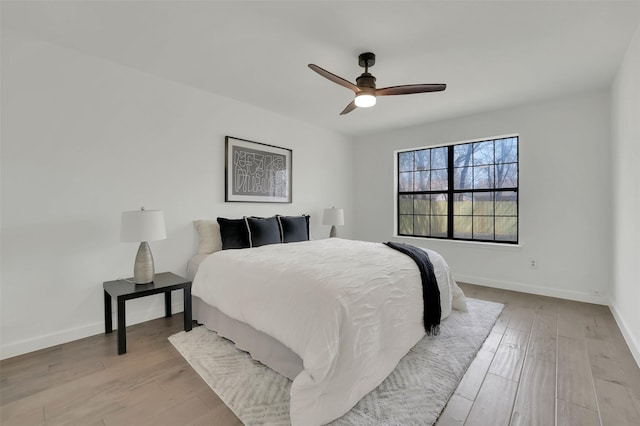 bedroom featuring ceiling fan, baseboards, and wood finished floors