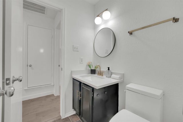 bathroom featuring visible vents, toilet, and vanity