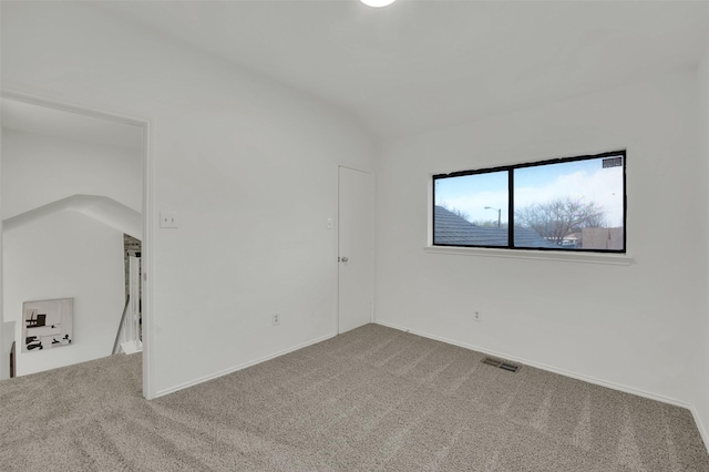 spare room with visible vents, carpet flooring, baseboards, and vaulted ceiling