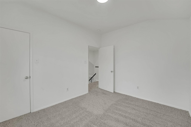 spare room featuring vaulted ceiling and carpet floors