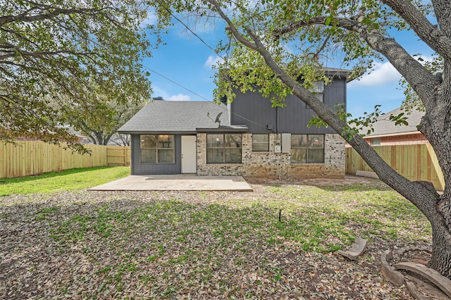 rear view of house featuring a patio, a yard, a fenced backyard, and brick siding